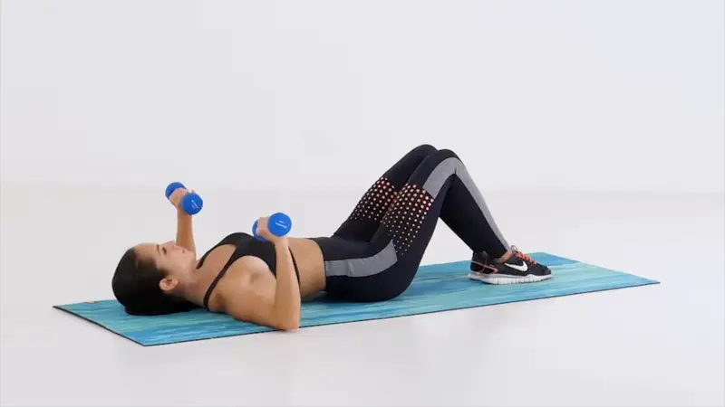 a woman is performing Dumbbell Chest Press on the floor_chest and triceps workout for women