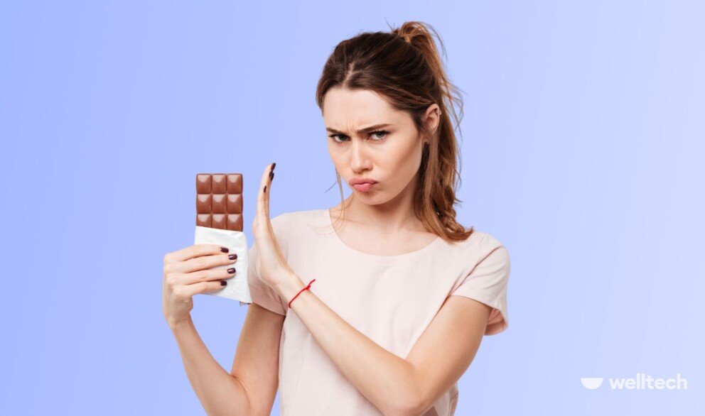 a woman is holding a chocolate bar and refusing to eat it_40 day sugar fast