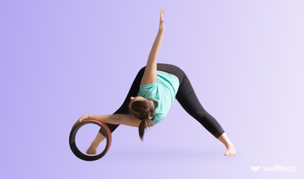 a woman is practicing yoga with a wheel, performing Revolved Wide-Legged Forward Bend (Parivrtta Prasarita Padottanasana)_yoga wheel stretches