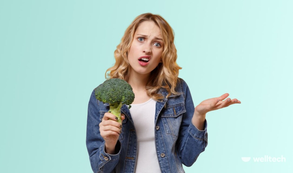 a woman is holding a broccoli_not losing weight on vegan diet