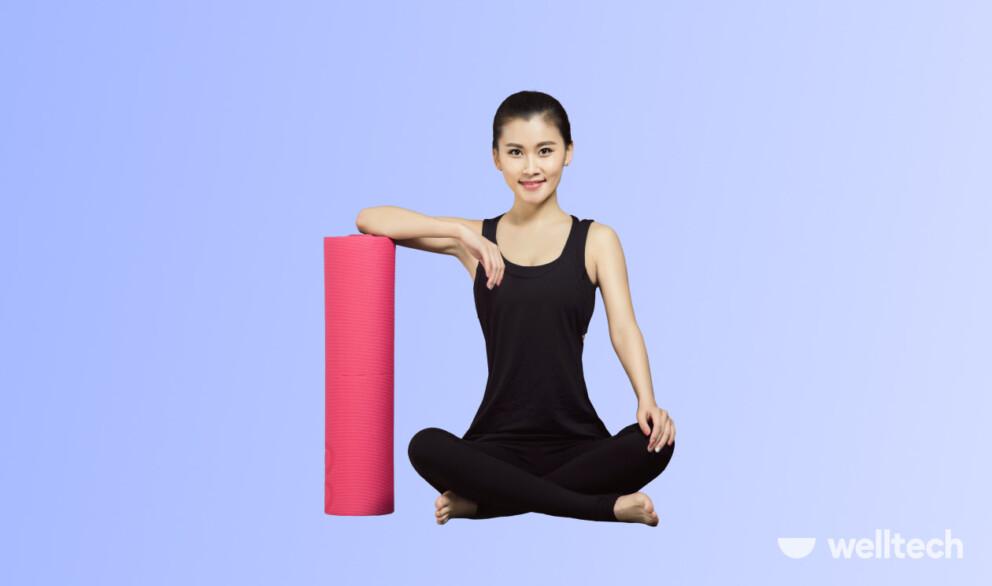 a woman is sitting in Easy Pose leaning on a rolled yoga matt, smiling, how often should you do yoga