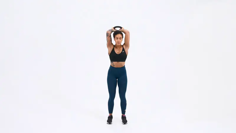 A woman is performing lateral head tricep exercises using a kettlebell overhead tricep extension.