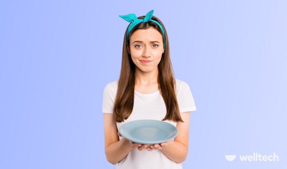 a young woman with a confused face is holding an empty plate, Why Am I Not Losing Weight In a Calorie Deficit