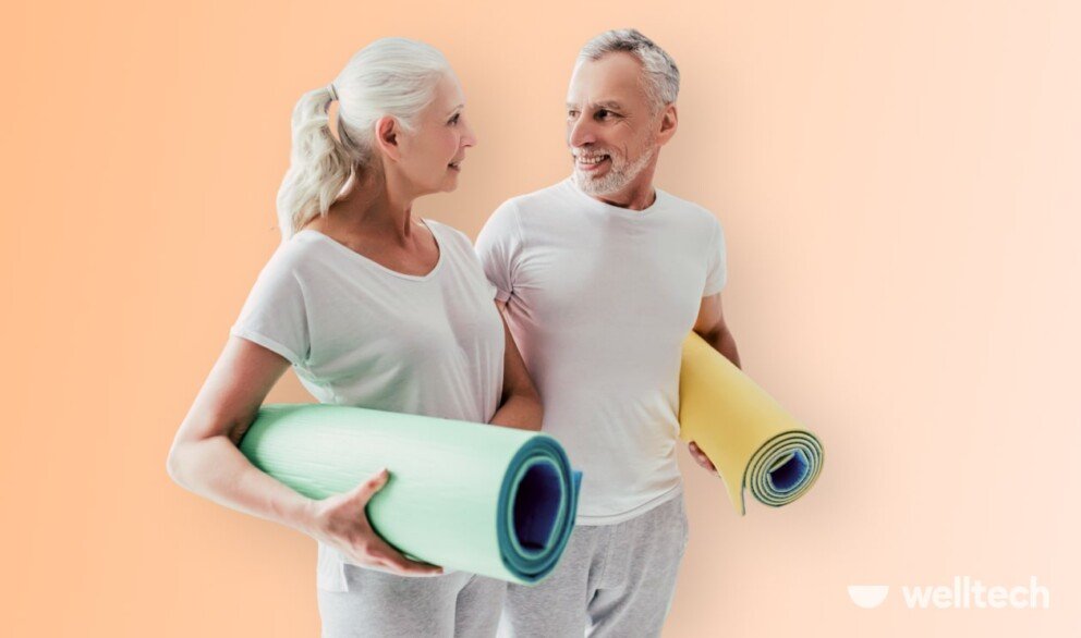 Senior couple, man and woman, are holding yoga mats, looking at each other, smiling, beginning yoga for seniors
