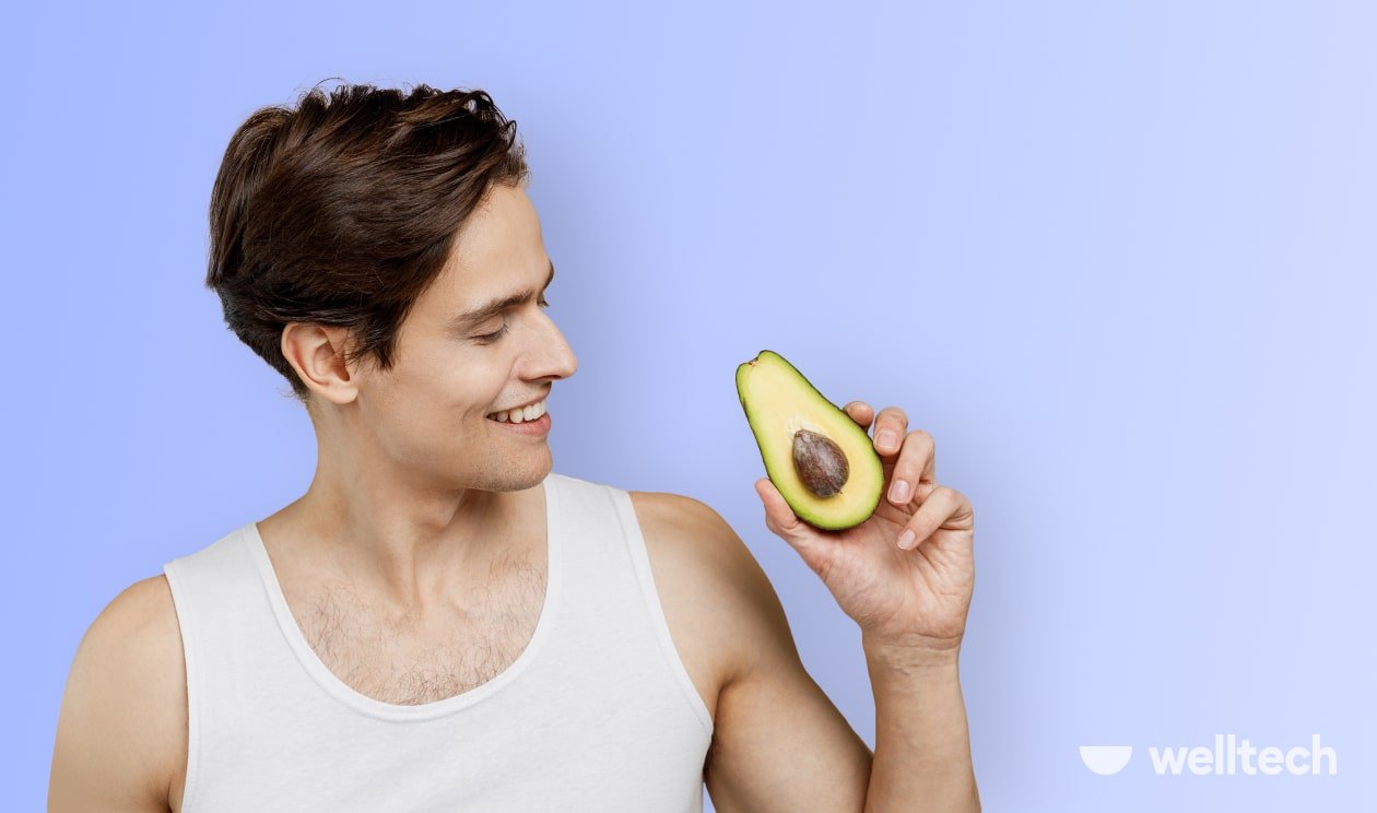 a young man is holding an avocado, smiling, keto diet for men
