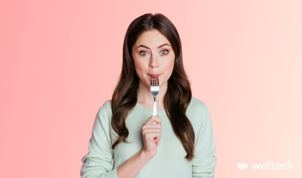 a woman is holding a tip of the fork in her mouth, hungry on intermittent fasting