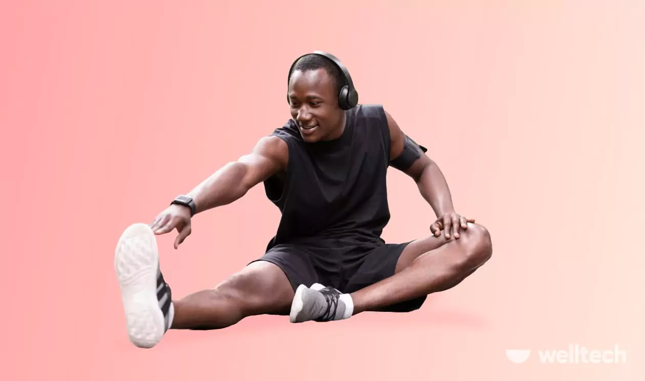 a man in black sportswear and headphones is stretching his leg, smiling, leg day warm-up