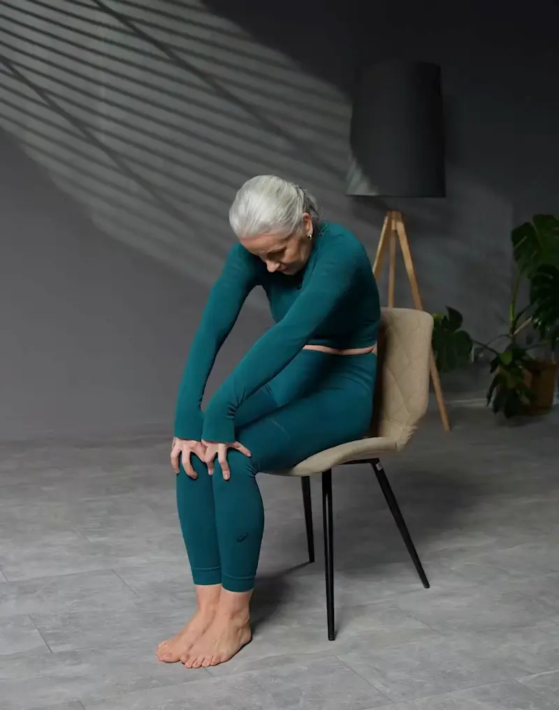 a senior woman is practicing chair yoga, performing cat and cow poses
