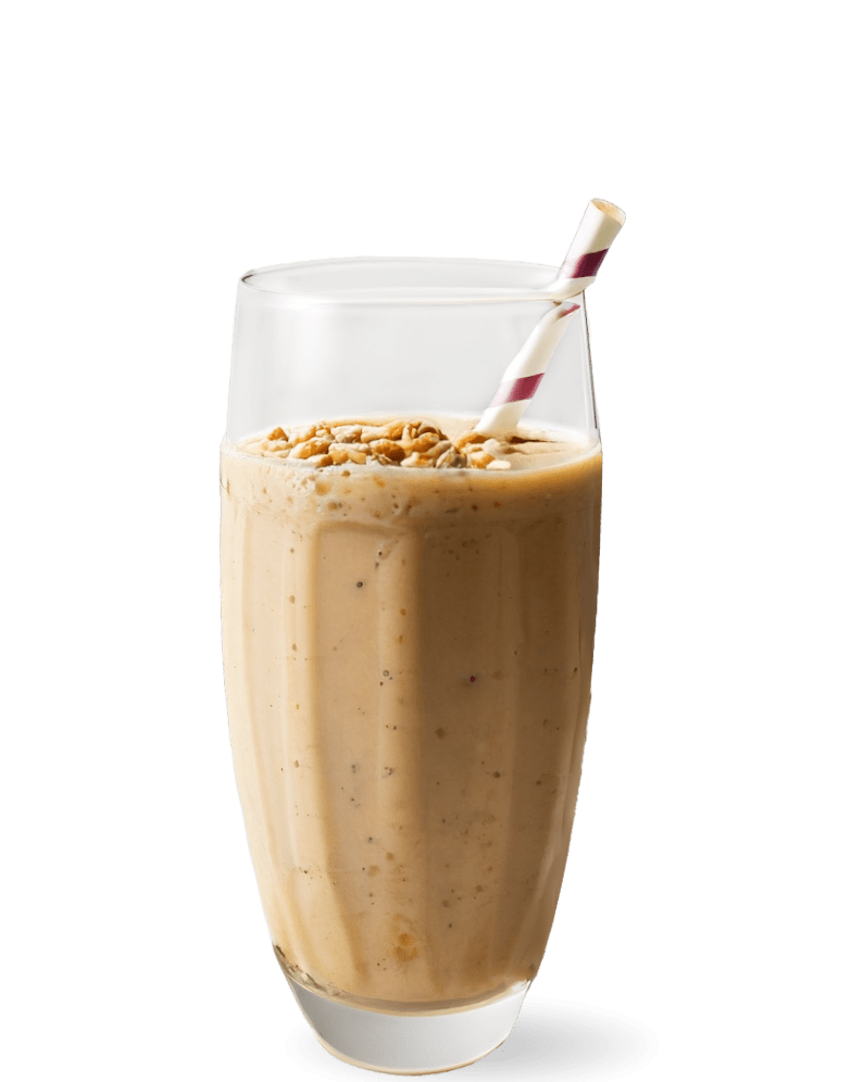 Mixed Nut Power Smoothie: A tall, clear glass is filled with a creamy, beige-colored smoothie, topped with a sprinkling of chopped nuts. A white straw with red stripes leans inside, ready for drinking. The visible texture of the smoothie is smooth with tiny flecks, suggesting a blend of various nuts and perhaps fruits or grains
