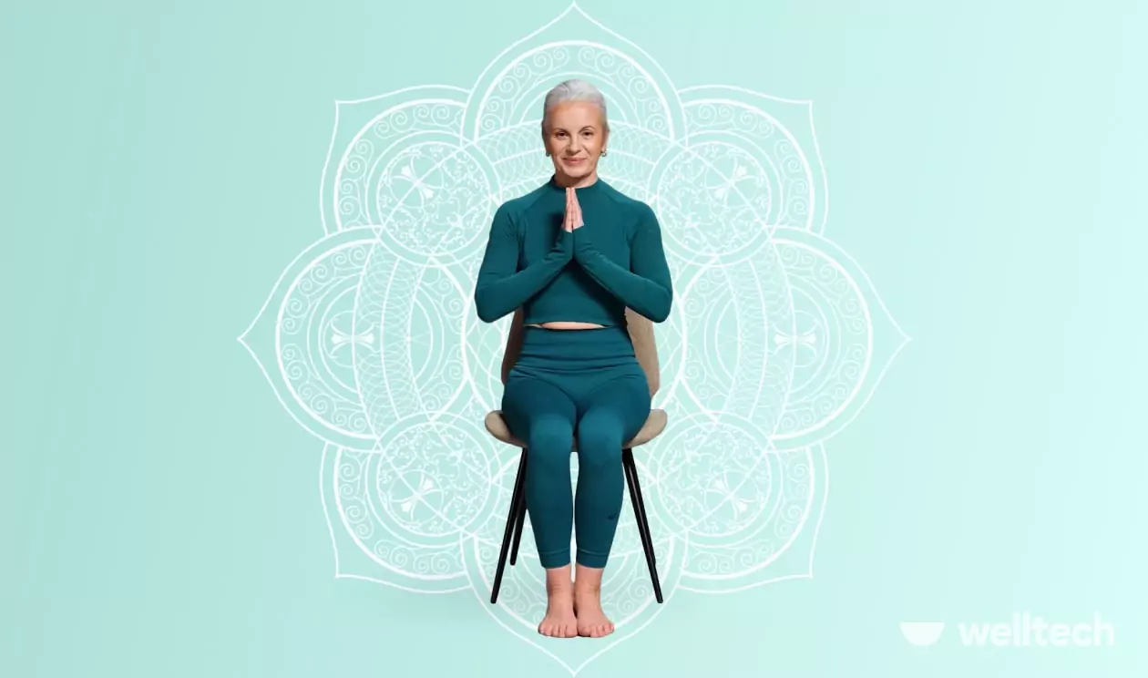an elderly woman is sitting on a chair, her hands are in namaste, chair yoga for seniors