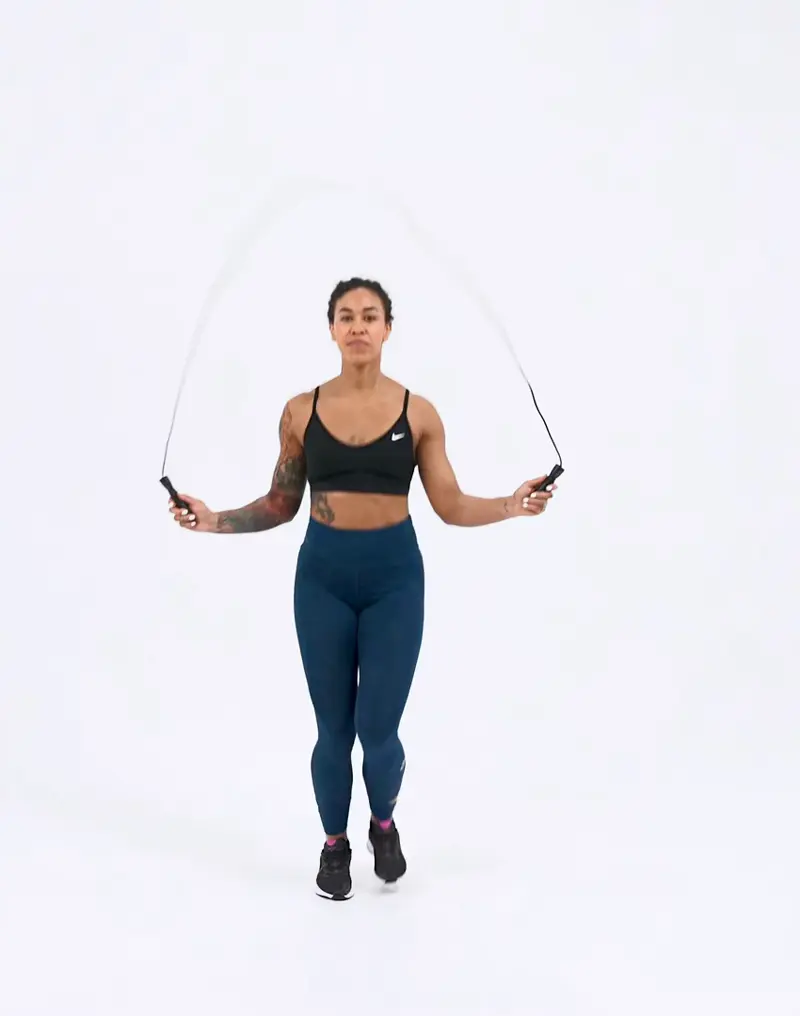 a woman is performing cardio legs workout, doing running in place, jumping rope