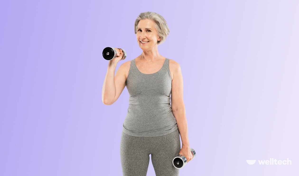 a mid aged woman (senior) with grey hair in grey sportswear is working out, holding dumbbells in both hands, strength training for women over 50