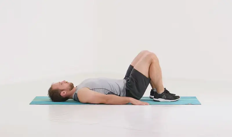 a man is working out, doing glute bridge_back exercises without weights