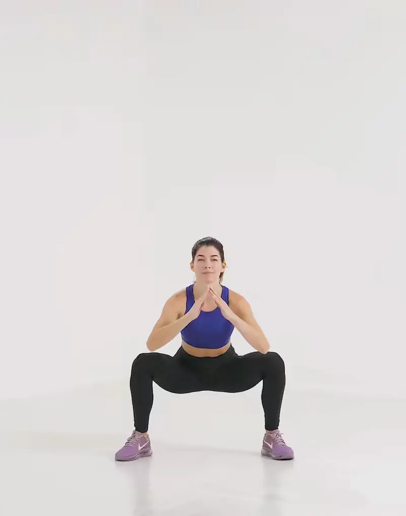 a woman is performing cardio legs workout, doing sumo squat jump