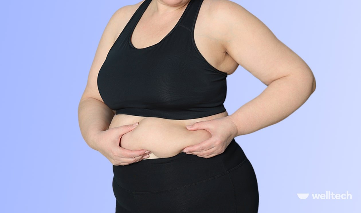 a curvy woman in a black two-piece set is holding her stomach fat, how to lose upper-body fat