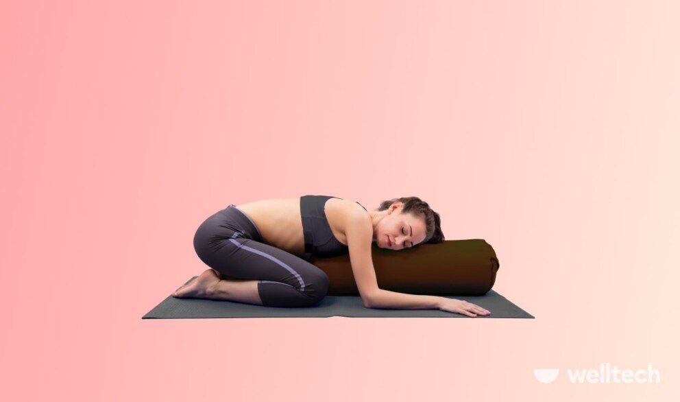 a woman is practicing yoga, doing childs pose with a bolster_yoga for period cramps